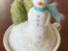 small felted snowman in a cup with trees